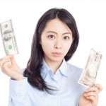 米ドルと日本円を持つ女性